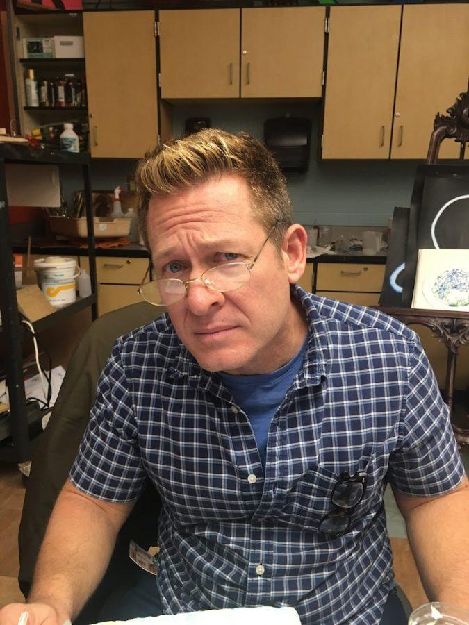 Kent Wallisch modeling glasses at his desk.