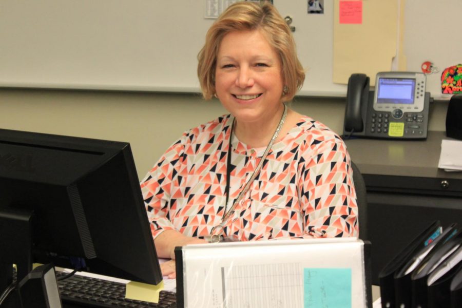 Mrs. Broderick is all smiles at her desk.
