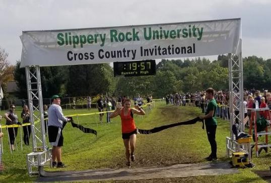 ARMS TRIUMPHANTLY RAISED, sophomore Emily Carter breaks the tape as she crosses the finish line in 1st place at the Slippery Rock Invite.