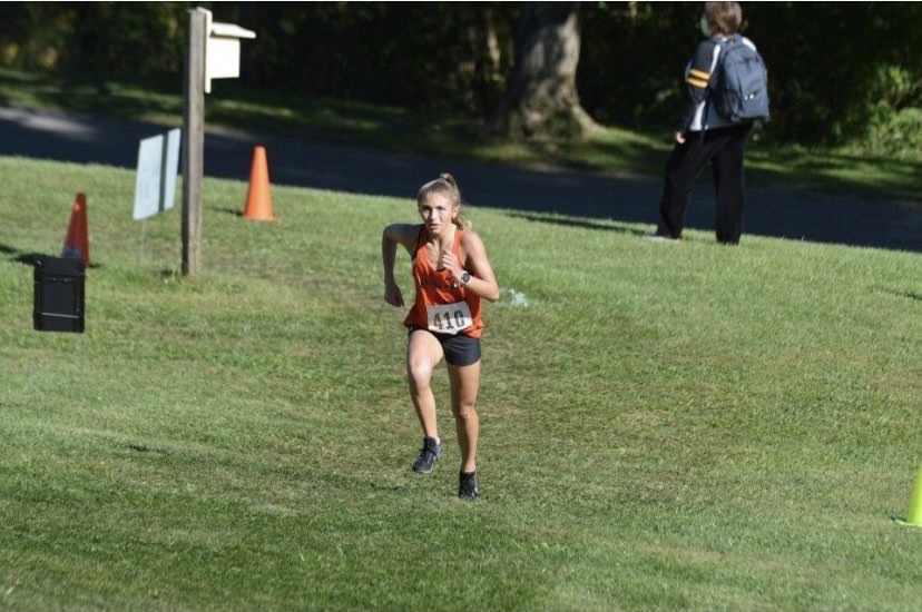 Jenna Lang runs up a hill at the Red, White, and Blue Invite at White Oak.
