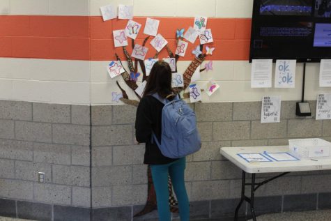 A student pauses and looks at the tree with names of lost loved ones written on butterflies.