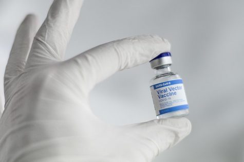 A pharmacist holding a COVID-19 vaccine vial.