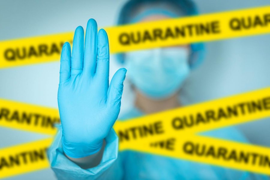Concept+quarantine+alert+with+blurred+doctor+with+mask+and+protective+suit%2C+doctor+and+isolation+with+yellow+ribbons+for+quarantine.