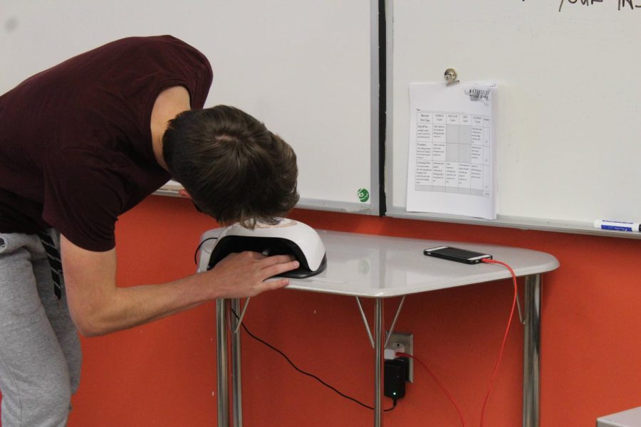 One of Mr. Wallischs Science and Art students dries his freshly painted nails under a nail dryer.