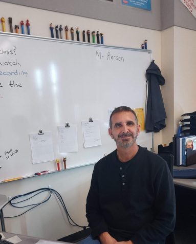 Mr. Pierson sits at his desk with some of his famous Pez dispensers above his board.